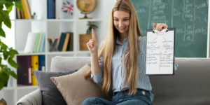 Woman sitting on couch holding a clipboard with notes.