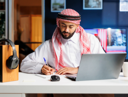 Arab man working on laptop in a cozy, well-lit home.