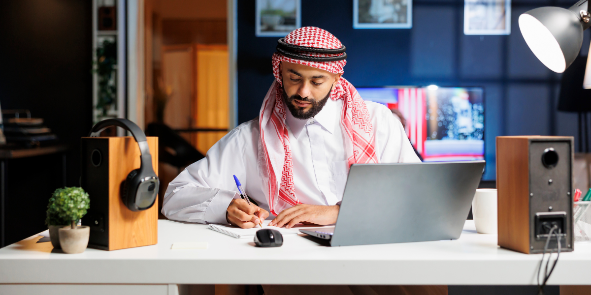 Arab man working on laptop in a cozy, well-lit home.