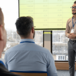 A man presenting to an audience, engaging with the group while using visual aids.