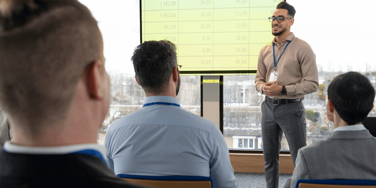 A man presenting to an audience, engaging with the group while using visual aids.