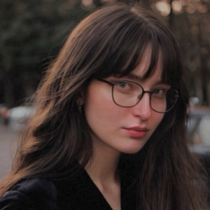 A woman wearing glasses and a black top, looking confidently at the camera.