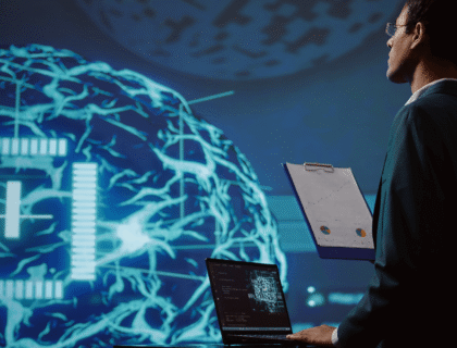 A man in a suit stands before a computer screen displaying an AI logo, suggesting a professional tech environment.
