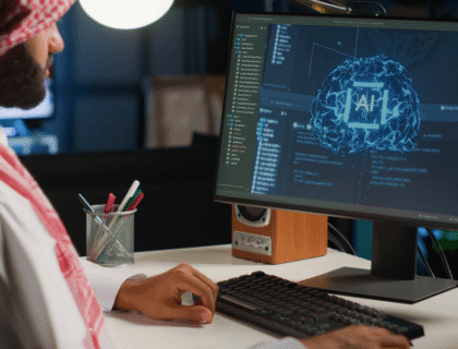 A man wearing a headscarf is focused on working at his computer.