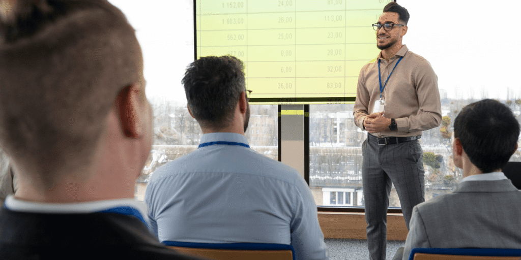A man presenting to an audience, engaging with the group while using visual aids.