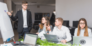 A diverse group of professionals working collaboratively at laptops in a modern office setting.