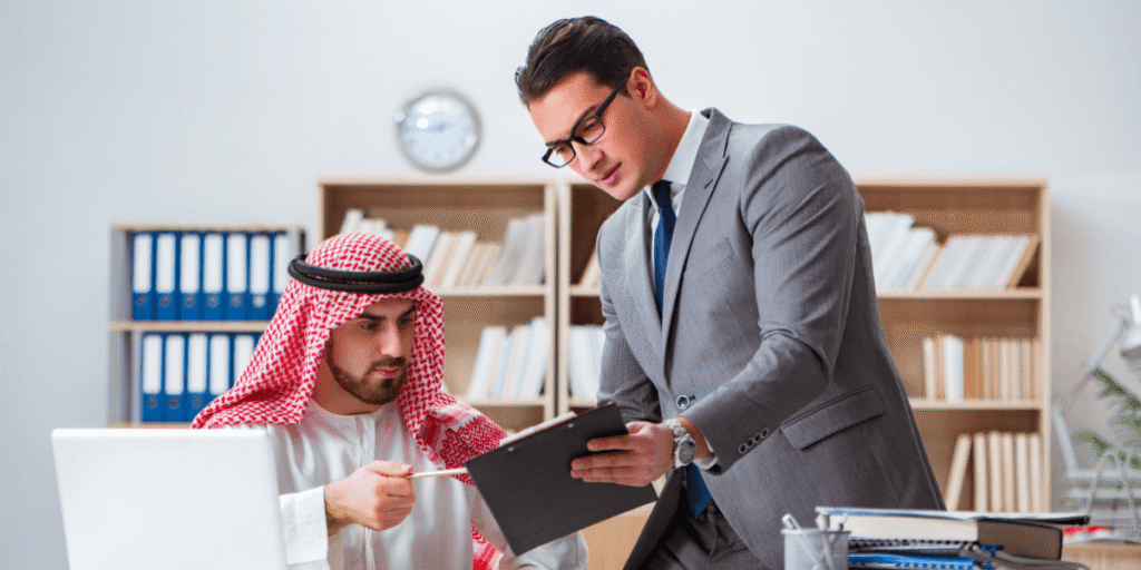 Two men in business suits collaborate on a laptop, discussing ideas in a professional setting.