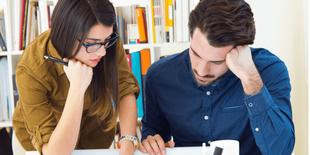 A man and woman collaborate on a project, discussing ideas while reviewing documents at a table.