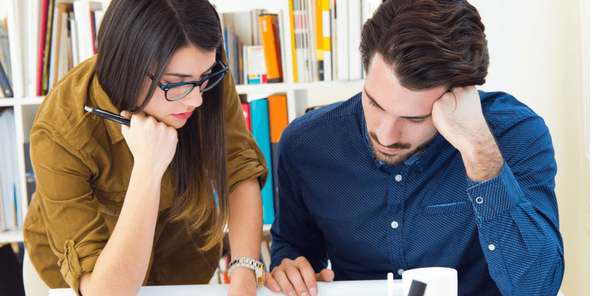 A man and woman collaborate on a project, discussing ideas while reviewing documents at a table.
